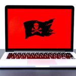 laptop with red screen and a black pirate flag