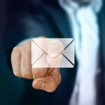 Email envelope on a screen with a man's finger pointing at it